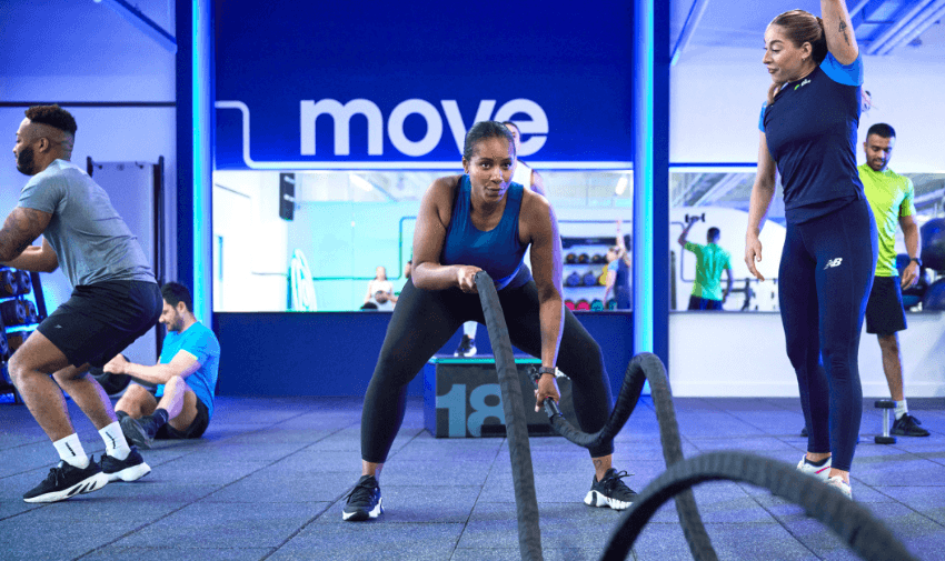 Woman in a blue top exercising with battle ropes at The Gym Group, showcasing inclusive workout spaces and mobility discounts and offers for disabled members.