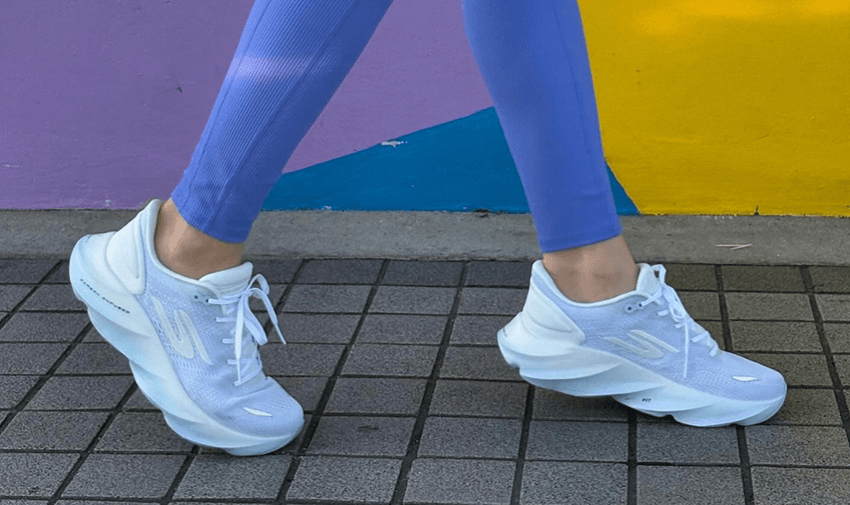 Person walking in white and lilac Skechers trainers paired with purple leggings against a colourful background – lightweight supportive trainers with disabled footwear discounts for active lifestyles and walking comfort.