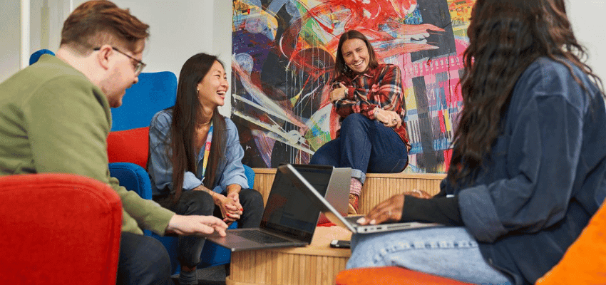 Colleagues chat with laptops in Virgin Media office, Purpl discounts for disabilities and long term health conditions, mobility discounts and offers.