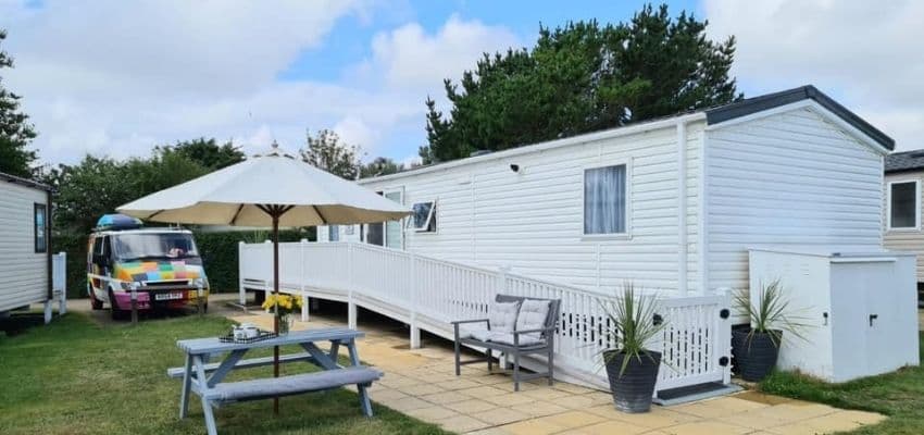 White holiday caravan with ramp and picnic bench; Purpl discounts for disabilities and long term health conditions, disabled travel discounts UK.