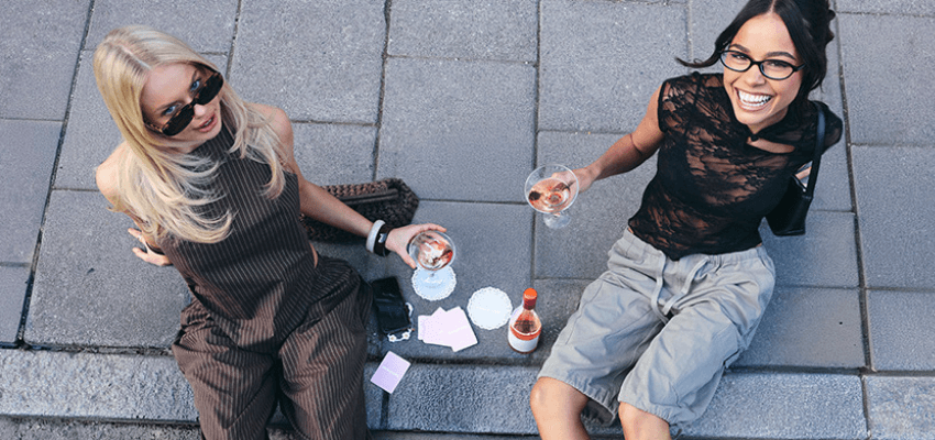 Two women sitting on pavement with drinks, Boohoo Purpl discounts for disabilities and long term health conditions, shopping discounts for disabled people.