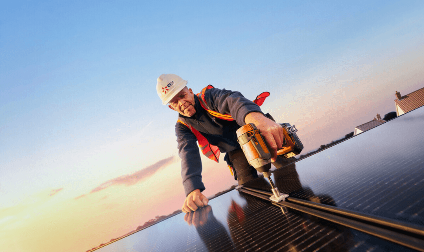 Engineer fits solar panel during sunset rooftop installation. Ideal for content on disabled homeowner energy discounts, accessible green energy savings and home upgrades.