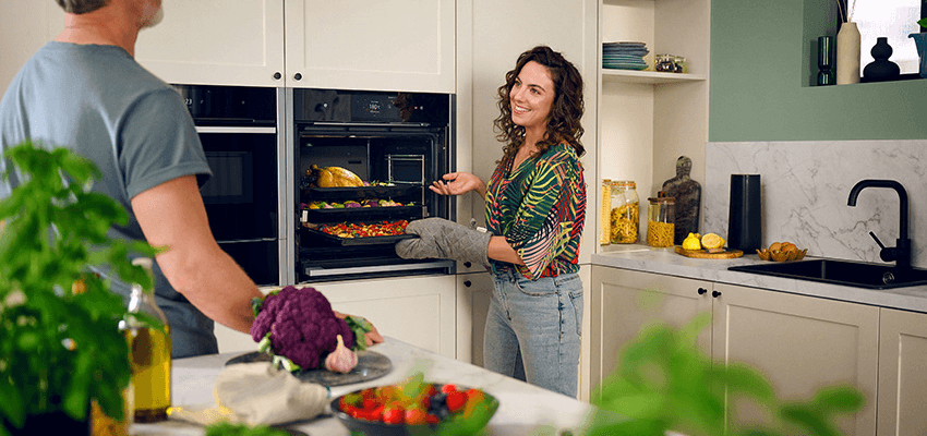 Woman cooking beside man in modern kitchen, Neff Purpl discounts for disabilities and long term health conditions, shopping discounts for disabled people.