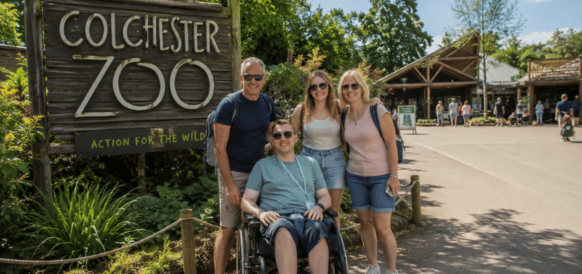 Family posing by Colchester Zoo sign, Purpl discounts for disabilities and long term health conditions, disabled travel discounts UK.