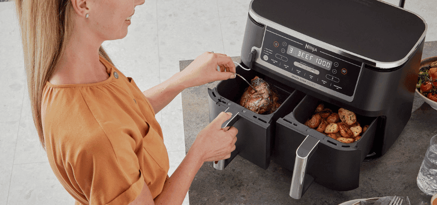 Woman cooking with Ninja dual air fryer on kitchen counter – exclusive kitchen appliance discounts for disabled people UK.
