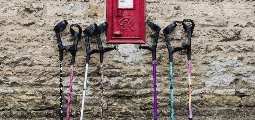 Colourful crutches lined against stone wall, Cool Crutches, Purpl discounts for disabilities and long term health conditions, mobility discounts and offers.