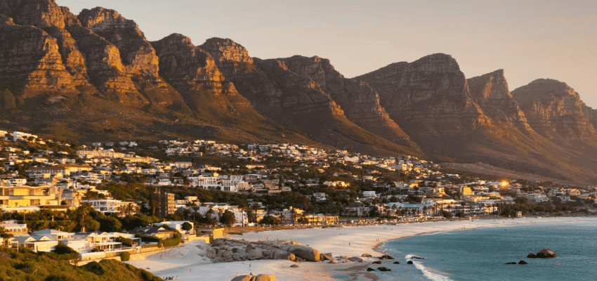 Coastal city and beach with mountains at sunset promoting accessible hotel stays with disabled travel discounts in the UK