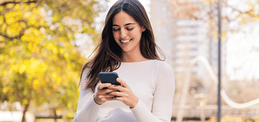 Smiling woman using smartphone outdoors, Reward Mobile, Purpl discounts for disabilities and long term health conditions, shopping discounts for disabled people.