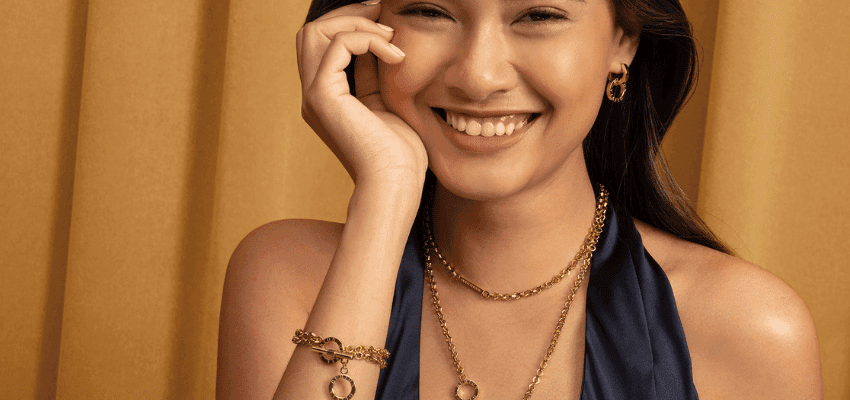 Woman wearing Olivia Burton gold jewellery and smiling, used for Purpl discounts content, supporting people with disabilities and long term health conditions with everyday savings.
