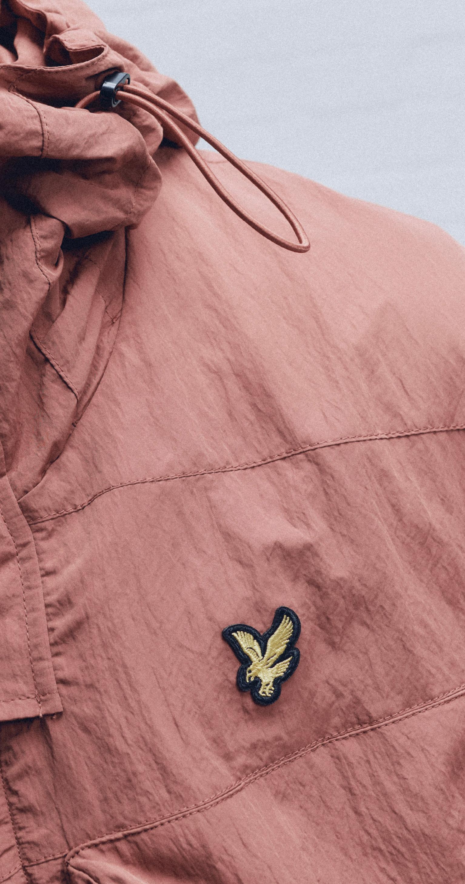 Close-up of a dusky pink Lyle & Scott jacket with signature yellow eagle logo, part of fashion discounts for disabled people through Purpl’s clothing and lifestyle offers.