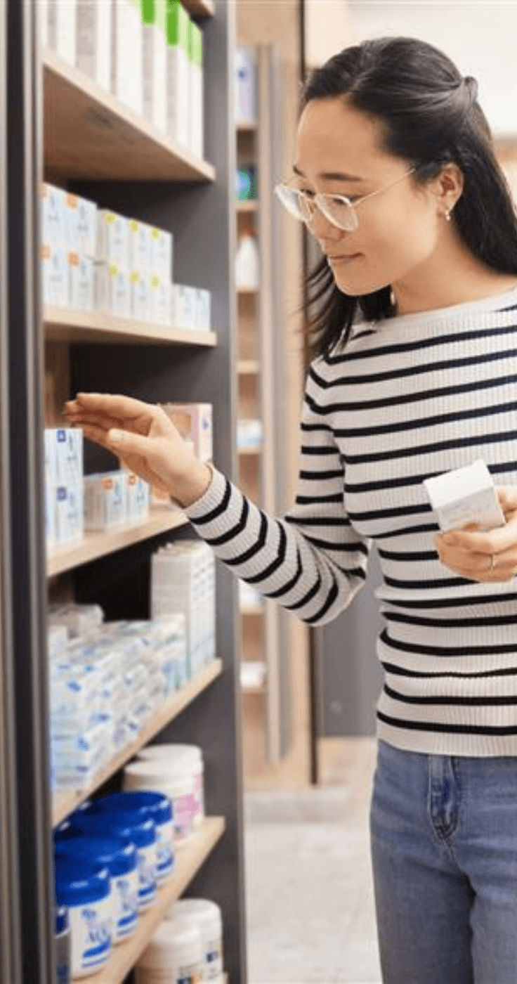 Young woman browsing medicine aisle at Pharmacy2U – NHS repeat prescriptions and personal healthcare discounts for disabled people in the UK.