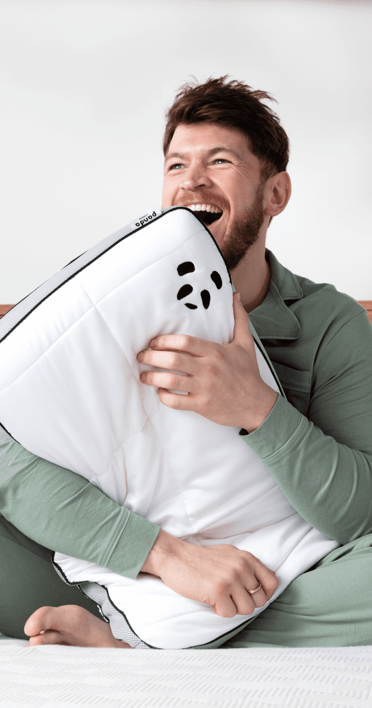 a man clutching a Panda pillow whilst sat on a Panda mattress