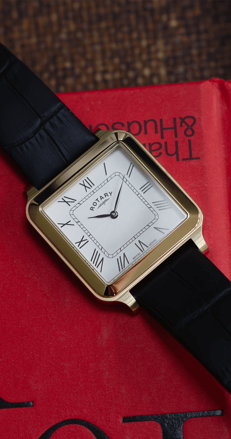 A gold rotary watch lying on a red book.