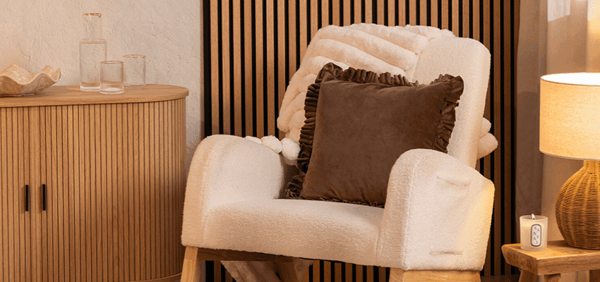 Cosy armchair with cushions beside a wooden cabinet and warm lamp, representing affordable home comfort items available through Purpl discounts for people with disabilities and long term health conditions looking for everyday savings on homeware.