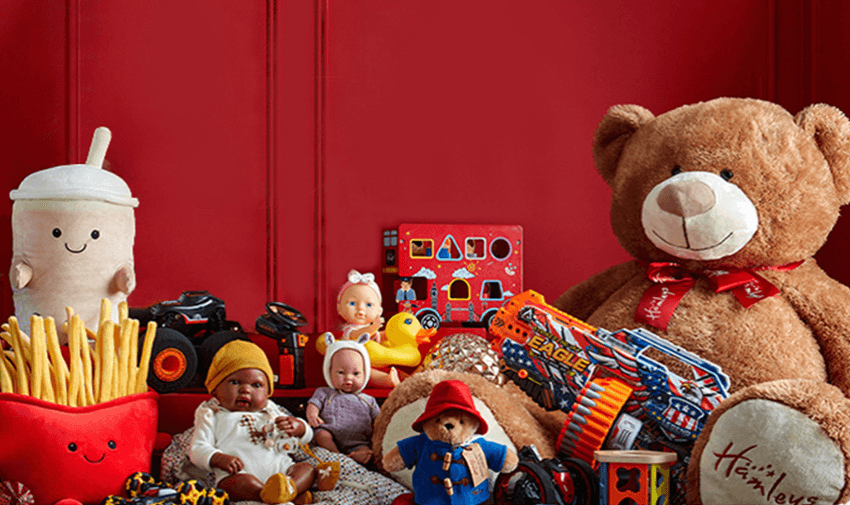 A collection of various toys, including a large teddy bear, dolls, a toy gun, and plush food items, against a red background, showcasing shopping discounts for disabled people.