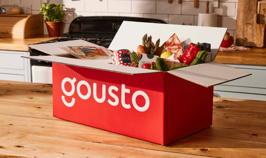 Red Gousto recipe box filled with fresh vegetables and ingredients on a kitchen table. Disabled grocery discounts UK, meal kit offers for disabled people.