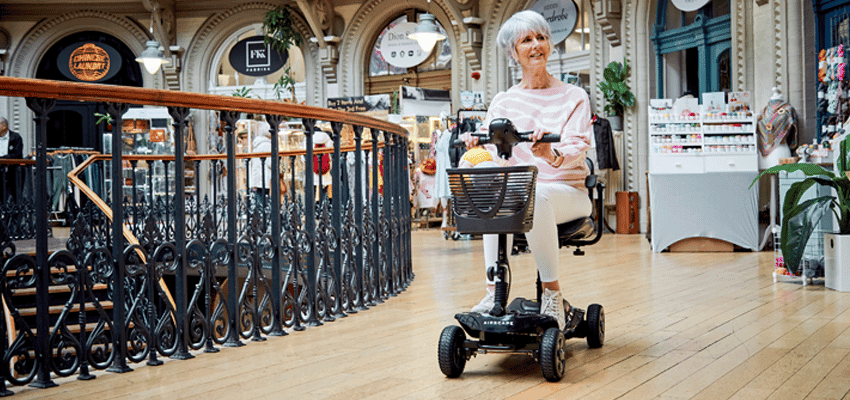 Woman riding mobility scooter in shopping arcade, Eden Mobility, Purpl discounts for disabilities and long term health conditions, mobility discounts and offers.