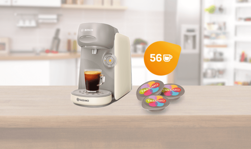 Cream Bosch Tassimo Finesse coffee machine brewing an espresso on a kitchen counter, with 56 colourful Tassimo pods beside it, highlighting accessible hot drinks bundle deals and inclusive home appliance discounts for disabled shoppers in the UK.