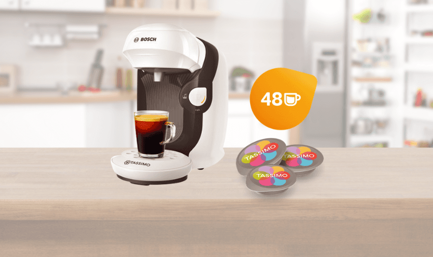 White and black Bosch Tassimo Style coffee machine brewing an espresso on a wooden kitchen counter, with 48 Tassimo pods beside it, showcasing budget-friendly coffee bundle offers and practical home discounts for disabled people across the UK.