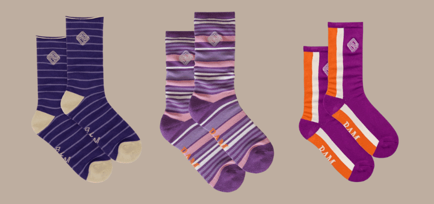 Three pairs of colourful BAM bamboo socks in shades of purple, lilac, orange, and cream displayed on a neutral background. Represents eco-friendly and sustainable clothing offers from BAM Clothing available through Purpl Disabled Discounts, perfect for comfort, softness, and style.