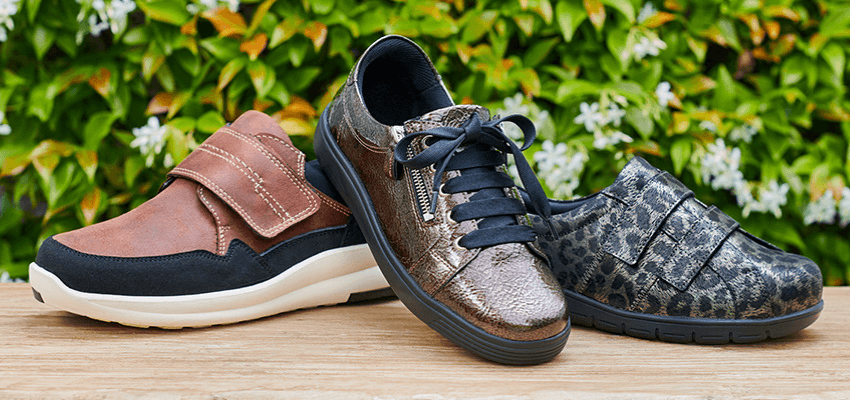Three Cosyfeet shoes displayed on a wooden table; Purpl discounts for disabilities and long term health conditions, mobility discounts and offers.