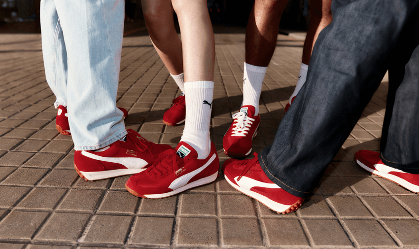 Group of people wearing matching red and white PUMA trainers with white socks, standing close together on a tiled pavement, highlighting inclusive style and accessible footwear deals for disabled people across the UK