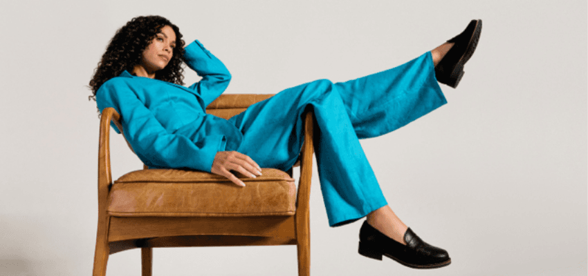 Woman in turquoise suit in armchair, Calla Shoes: Purpl discounts for disabilities and long term health conditions, mobility discounts and offers.