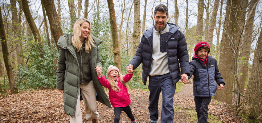 A family wearing Regatta coats while walking through the woods, promoting Regatta outdoor clothing with shopping discounts for disabled people and savings for those with long term health conditions.