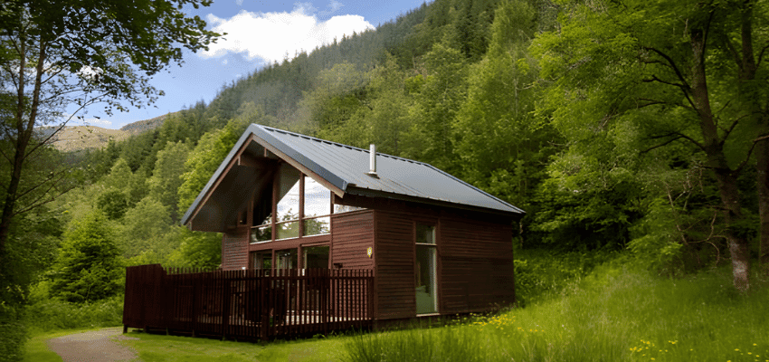 Wooden holiday cabin surrounded by forest and hills promoting accessible UK breaks with disabled discounts on countryside stays