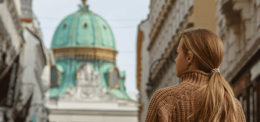 Woman walking through historic European street towards landmark building promoting city break hotels with disabled discounts in the UK