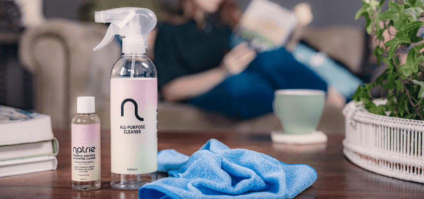 Natrie all purpose cleaner and concentrated refill beside a blue cleaning cloth in a home setting, available through Purpl discounts.