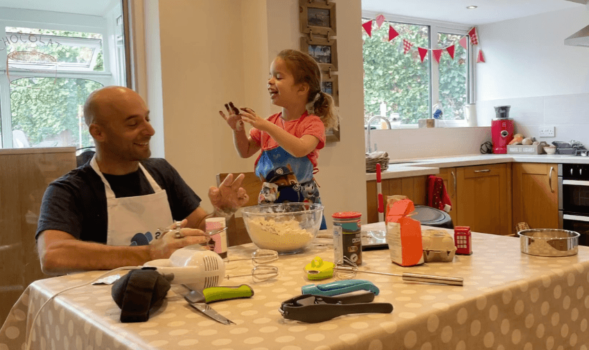 Dad and daughter laughing together while baking, surrounded by accessible kitchen tools on the table, capturing joyful family life and everyday independence with mobility discounts and offers.