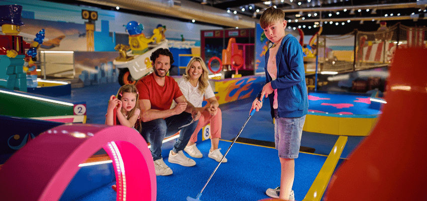 Family playing indoor mini golf at LEGOLAND® Adventure Golf, Purpl discounts for disabilities and long term health conditions, disabled travel discounts UK.