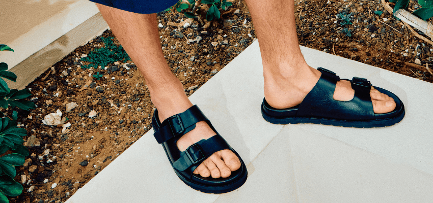 Black leather sandals on tiled outdoor path, Schuh Purpl discounts for disabilities and long term health conditions, mobility discounts and offers.