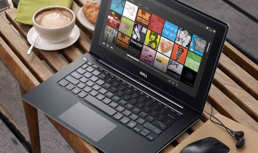 Dell laptop on a wooden table beside a cappuccino, showcasing flexible tech for remote working with exclusive laptop savings for disabled users in the UK.