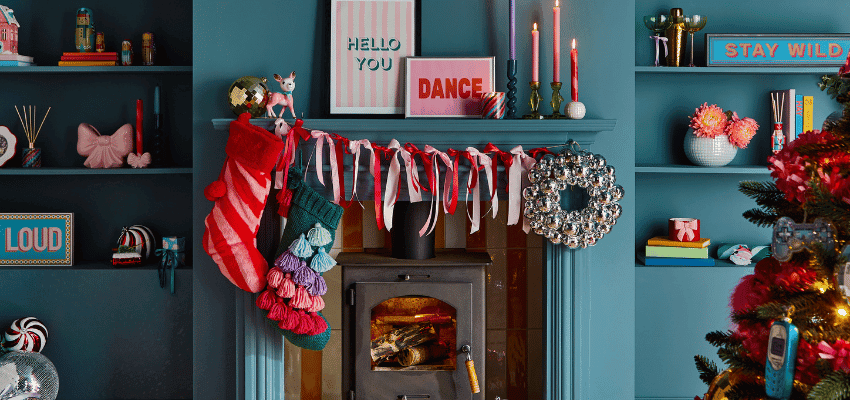 Festive Dunelm living room decorated with bold colourful stockings, ribbon garlands and a cosy fireplace, used for promoting Dunelm Christmas homeware through Purpl discounts for people with disabilities and long term health conditions, including shopping discounts for disabled people and accessible home décor savings.
