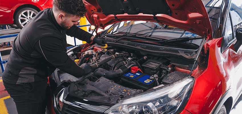 Mechanic servicing a red car engine at Kwik Fit; Purpl discounts for disabilities and long term health conditions, mobility discounts and offers.