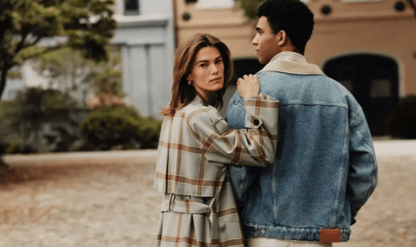 Man in denim jacket and woman in checked coat standing outdoors promoting Tommy Hilfiger