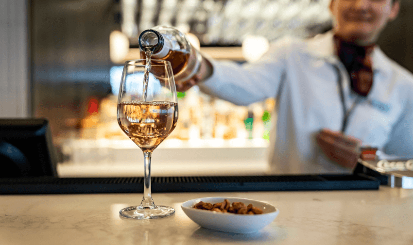 Bartender pouring a glass of wine in a relaxing airport lounge, ideal for showcasing accessible airport experiences and UK travel discounts for disabled people.
