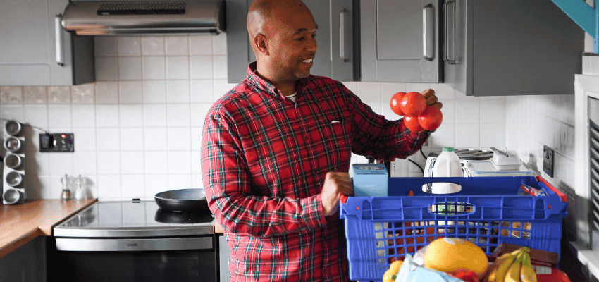 Man unpacking Tesco groceries in kitchen, Purpl discounts for disabilities and long term health conditions, shopping discounts for disabled people.