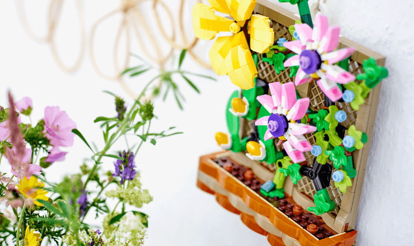 LEGO Flower Trellis wall build featuring bright yellow and pink brick flowers alongside real wildflowers, showcasing mindful crafting kits and therapeutic sensory toys for disabled children in the UK.