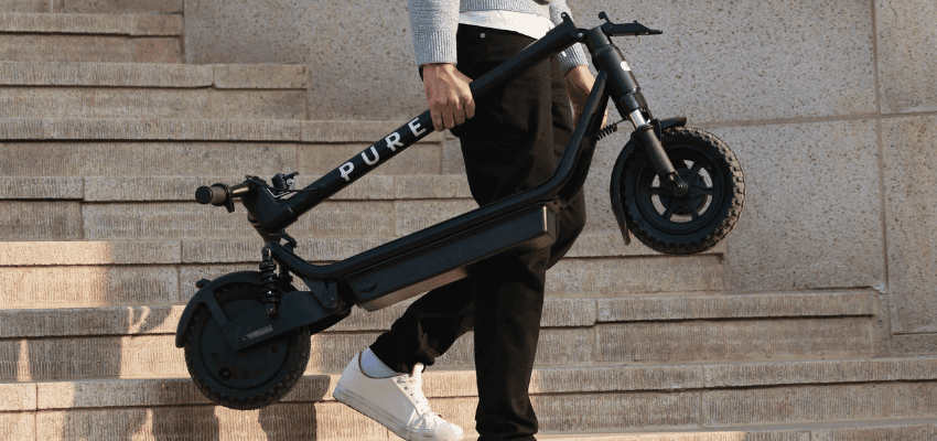 Person carrying folded e-scooter on steps, Currys Purpl discounts for disabilities and long term health conditions, mobility discounts and offers.