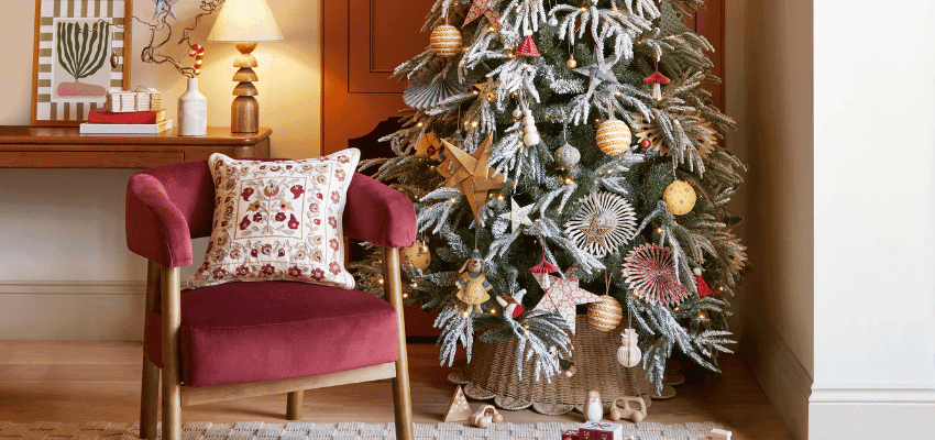Elegant Christmas tree with gold and white decorations beside a red velvet chair in a stylish Dunelm room, supporting a Purpl discounts offer for people with disabilities and long term health conditions, featuring accessible Christmas homeware deals and seasonal shopping savings.