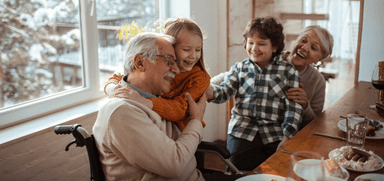 Grandparents and children smiling around the table, winter scene outside. Perfect for content about family energy savings, winter bills, and inclusive home energy support for disabled people and older adults.