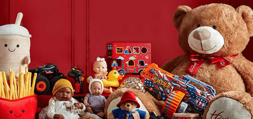 A collection of various toys, including a large teddy bear, dolls, a toy gun, and plush food items, against a red background, showcasing shopping discounts for disabled people.