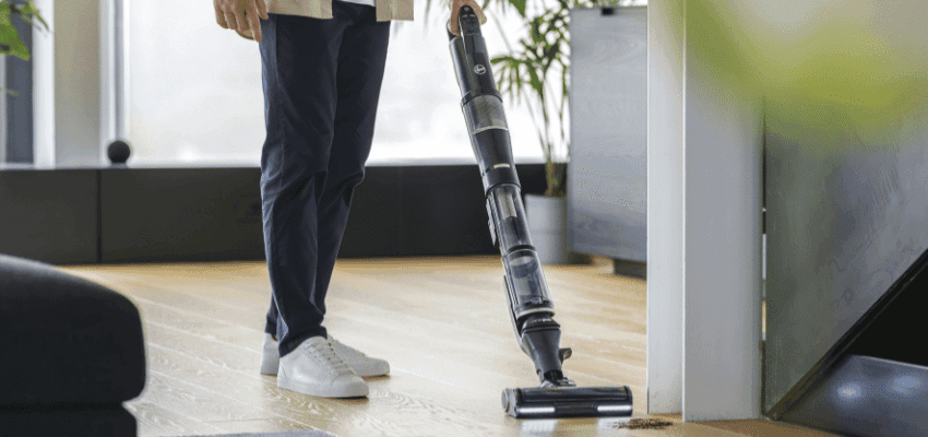 Person using a lightweight cordless Hoover vacuum on wooden floors, showing accessible cleaning solutions from Purpl home appliance discounts.