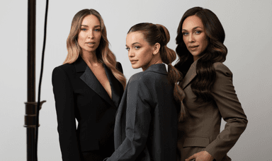 Three stylish women with long flowing hair wearing tailored blazers in black, grey and taupe, standing against a white background, highlighting premium hair styling products available with disabled beauty discounts in the UK.