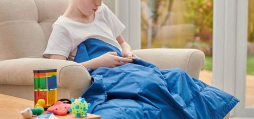 Child relaxing with tablet under blue blanket, Sensory Direct Purpl discounts for disabilities and long term health conditions, mobility discounts and offers.