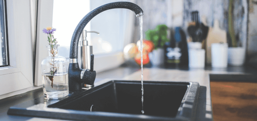 Kitchen tap running water into a dark sink beside a small glass vase Purpl discounts shopping discounts for disabled people accessibility discounts UK mobility discounts and offers savings for people with long term health conditions cost of living help for disabled people