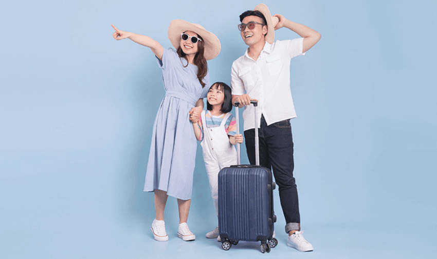 A cheerful family of three dressed for a holiday, standing with their luggage against a light blue background, representing secure and carefree travels. 